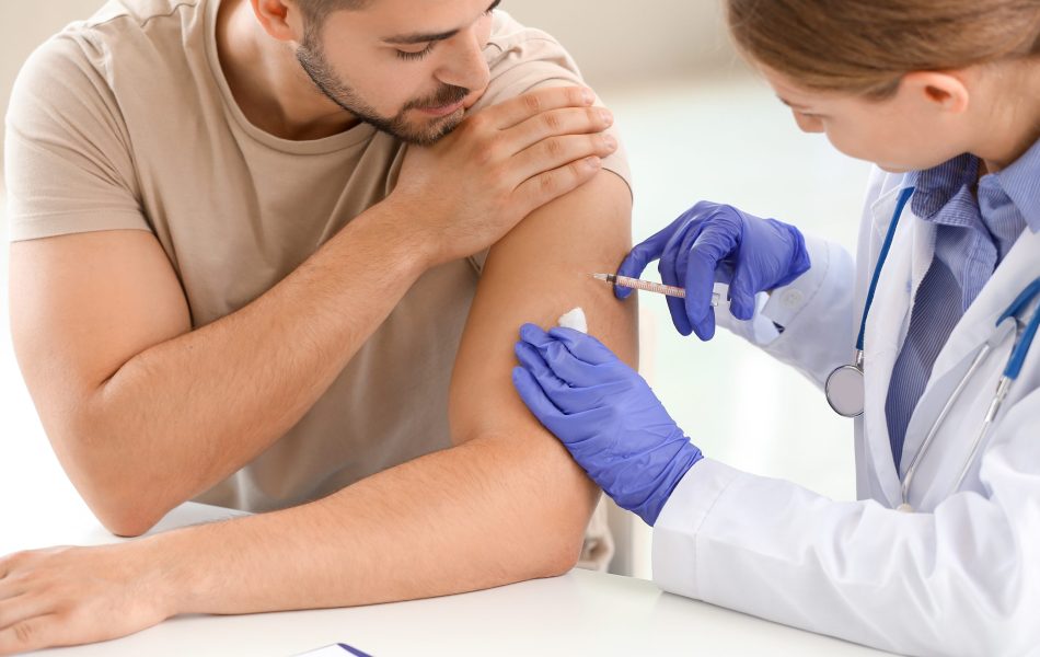 Doctor vaccinating young man in clinic